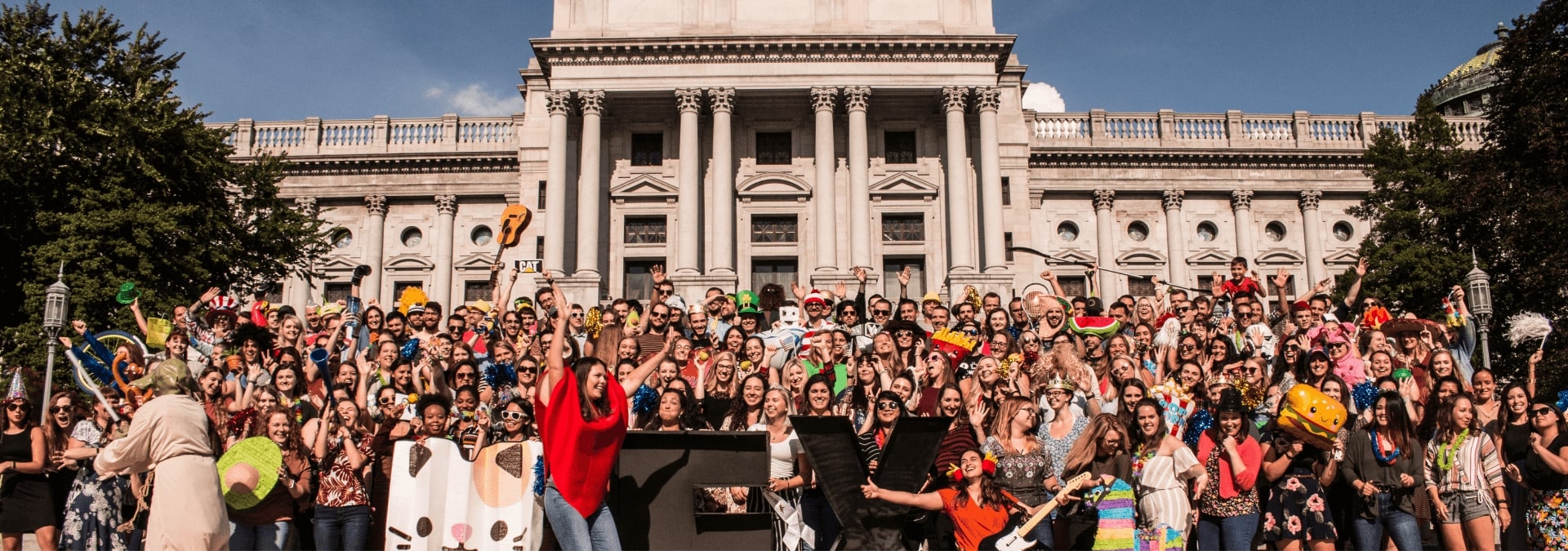 the WebFX team standing in front of the Pennsylvania Capitol building wearing props and smiling